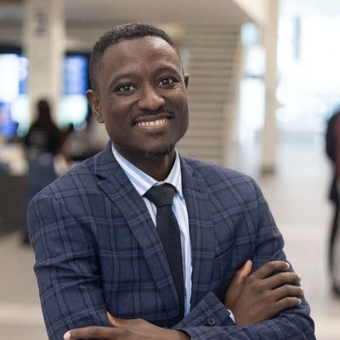 Bolade Onilari smiling in a navy checked suit
